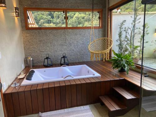 a bath tub in a bathroom with a glass shower at Matha Pousada e Bistrô in Lumiar