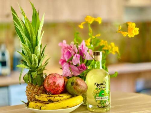 a plate of fruit and a bottle of juice and flowers at LA PLAYA - L'Appartement COZY - 2 à 5 personnes in Sainte-Anne