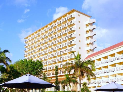 a large white building with umbrellas in front of it at Hotel Breezebay Marina in Miyako-jima