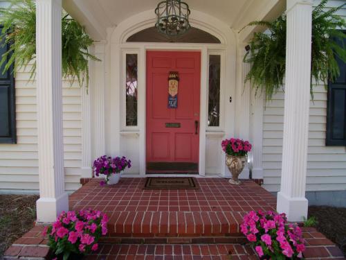 a red door on a white house with purple flowers at The Capitol Inn in Tallahassee