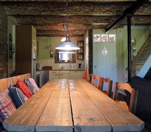 a large wooden table in a room with a kitchen at Vakantieboerderij Ferme Le Bleuet in Ohey