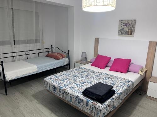 - une chambre avec 2 lits dotés d'oreillers roses et violets dans l'établissement Orly Pobla de Farnals playa, à Las Canteras