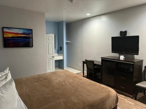 a bedroom with a bed and a flat screen tv at Moonlite Inn in Redondo Beach