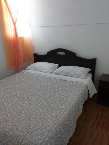 um quarto com uma cama com um edredão branco e uma janela em Hostal Las Cruces em Arica