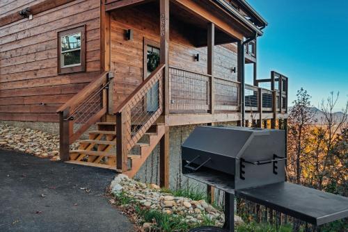 a log cabin with a porch and a grill in front of it at New Luxury Cabin with Stunning MountainVIEWS,HotTub, FirePit, FirePlace,2 KingBeds, 2 CoveredDecks,BBqGrill, ShuffleBoard and Pool Access in Sevierville