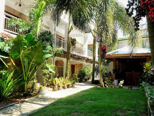 a garden in front of a building with palm trees at Senare Boracay Hotel in Boracay