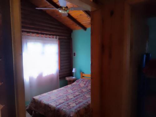 1 dormitorio con cama y ventana con cortina en CABAÑA LOS SAUCES en San Clemente del Tuyú