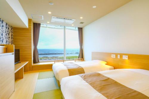 a hotel room with two beds and a large window at Ooedo Onsen Monogatari Premium Shiomiso in Murakami