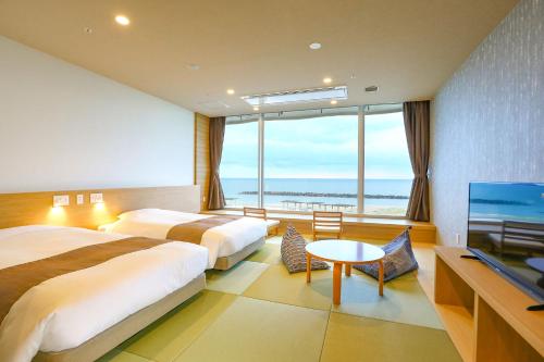 two beds in a hotel room with a large window at Ooedo Onsen Monogatari Premium Shiomiso in Murakami