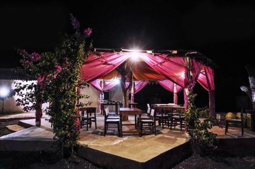 a pink tent with tables and chairs under it at night at Surkhab rann resort in Dhordo