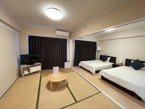a hotel room with two beds and a television at Stay Hakata in Fukuoka