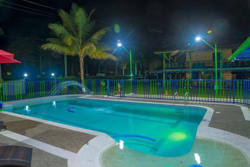 a swimming pool at night with a palm tree at La Casita del Sendero in Calarcá