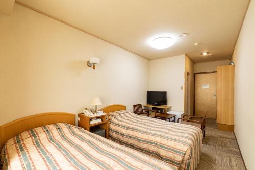 a room with two beds and a desk and a television at Ooedo Onsen Monogatari Kounkaku in Osaki