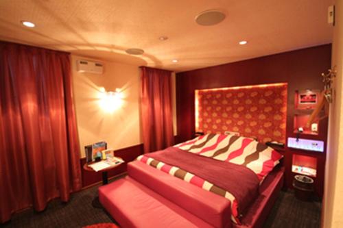 1 dormitorio con 1 cama grande y cabecero rojo en ROOM龍ヶ崎 -Adult only-, en Ushiku