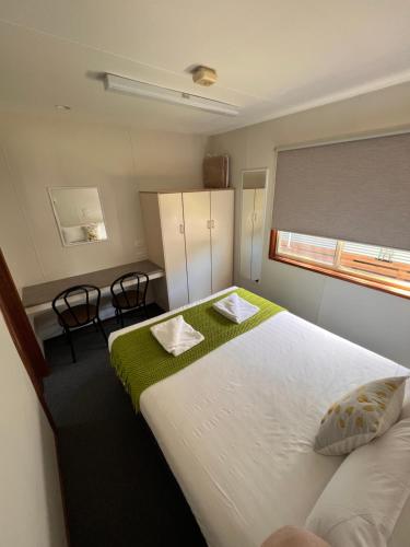 a bedroom with a large white bed with a green blanket at Ocean Grove Holiday Park in Ocean Grove
