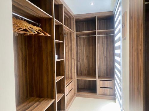 a walk in closet with wooden walls and shelves at Elegant 3 Bedroom Space Available in Accra
