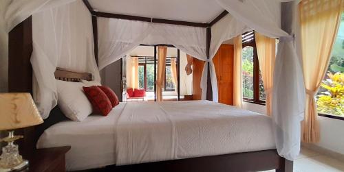 - une chambre avec un lit blanc à baldaquin dans l'établissement Sari Kembang villa ubud, à Ubud