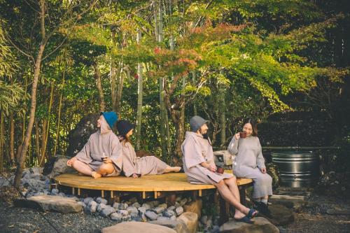a group of people sitting on a wooden bench at Uwanosora Bed&BBQ&Sauna in Shizuoka