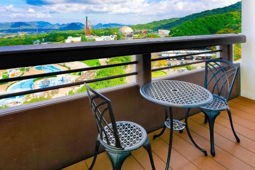 two chairs and a table on a balcony with a view at Ooedo Onsen Monogatari Hotel Reoma no Mori in Marugame