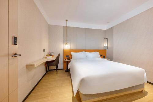 a hotel room with a large white bed and a desk at Real Joy Light in Shenzhen