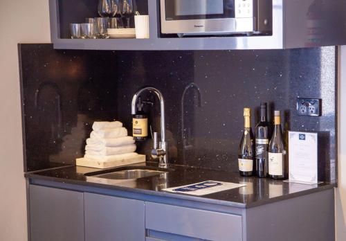 um balcão de cozinha com garrafas de vinho e um lavatório em Bayswater Boutique Lodge em Sydney