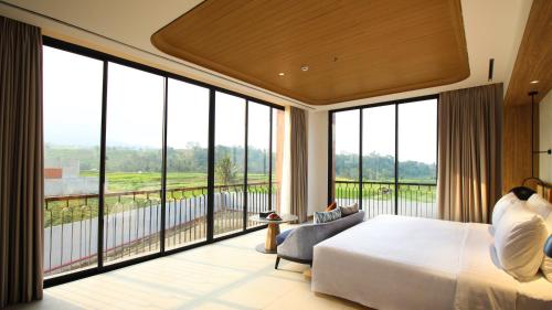 a bedroom with a large bed and large windows at Hotel Santika Premiere Linggarjati - Kuningan in Kuningan