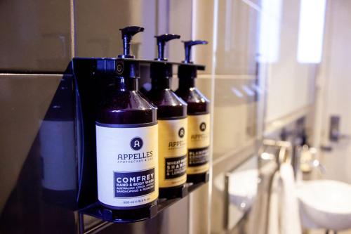 un grupo de cuatro botellas en un estante en un baño en Bayswater Boutique Lodge en Sídney