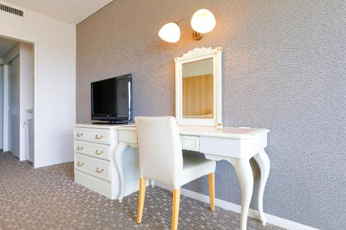a room with a desk with a tv and a mirror at Ooedo Onsen Monogatari Hotel Reoma no Mori in Marugame