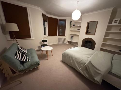 a bedroom with a bed and a chair and a table at Spacious room near underground in London