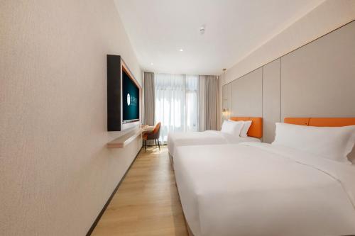 a hotel room with two beds and a flat screen tv at Real Joy Light in Shenzhen
