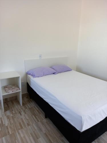 a bedroom with a white bed with purple pillows at Apartamento Vila Telebrasilia in Brasilia