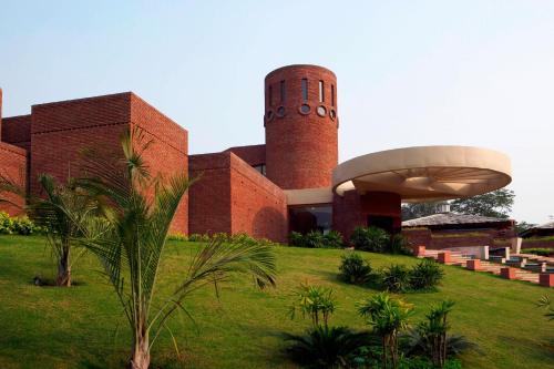 a building with a clock tower and a palm tree in front at The Westin Sohna Resort & Spa in Gurgaon