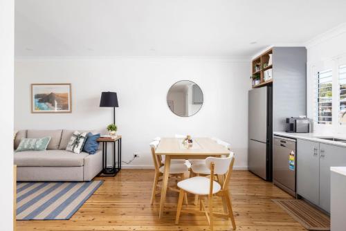 a kitchen and living room with a table and a couch at Shoal Bay Beach House One in Shoal Bay