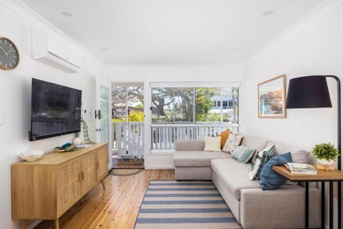 a living room with a couch and a tv at Shoal Bay Beach House One in Shoal Bay
