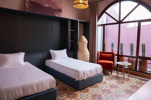 Un dormitorio con dos camas y una silla y una ventana. en Casa Maka, en San Luis Potosí