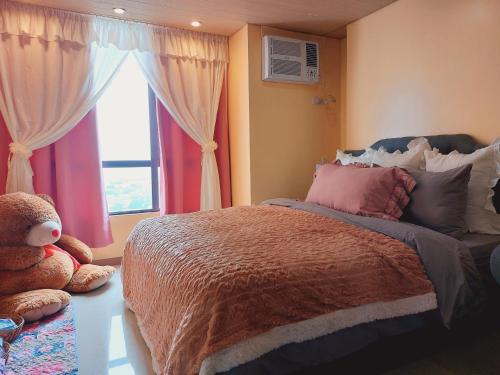 a bedroom with a bed and a window and a teddy bear at Congressional Town Center in Manila