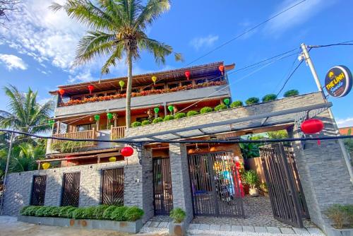 a building with a palm tree in front of it at The Linh Seaside Villa Hoi An in Hoi An