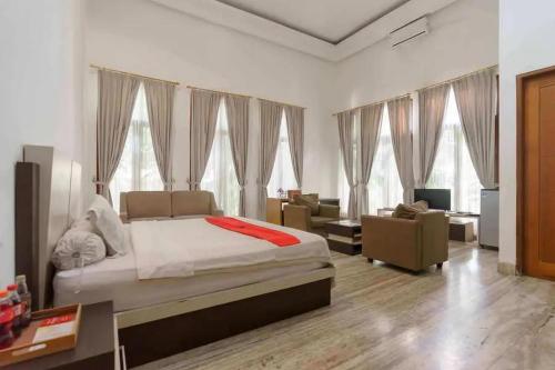 a bedroom with a bed and a living room with windows at RedDoorz Premium @ Gandaria Jagakarsa in Jakarta