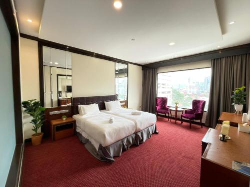 クアラルンプールにあるKingston Hotel Kuala Lumpurのベッドと大きな窓が備わるホテルルームです。