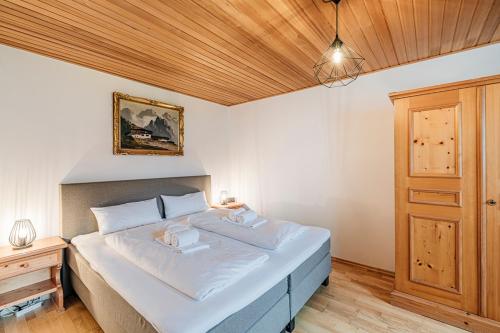 a bedroom with a white bed with a wooden ceiling at Ferienwohnung Michael - ruhig gelegen und nah am See in Schliersee