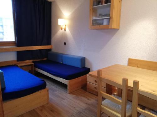 a room with a table and a blue bed and a table and chairs at Appartement Valmorel, 1 pièce, 4 personnes - FR-1-356-284 in Valmorel