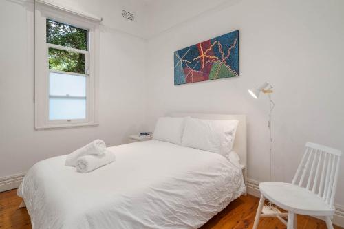 a white bedroom with a white bed and a chair at Charming 3 Bedroom Artist House in Mosman in Sydney