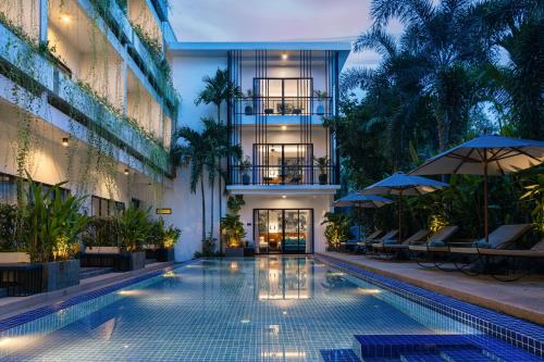 a swimming pool in a building with chairs and umbrellas at Grand Yard La Residence in Siem Reap