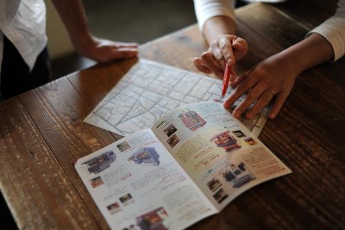 a person is writing on a newspaper on a table at 1166 Backpackers in Nagano
