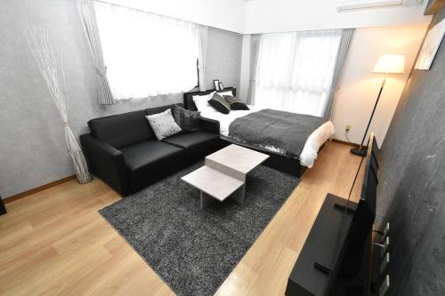 a living room with a bed and a black couch at coco de minpaku 今泉 in Susakiuramachi