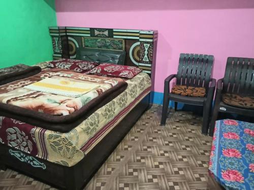 a bedroom with a bed and two chairs at Bajwal Home-Stay & Guest-House in Sari