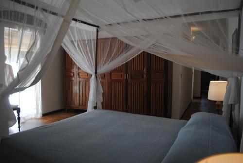 a bedroom with a canopy bed with white drapes at Villa Palissandre in Nosy Be