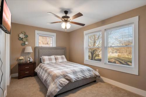 a bedroom with a ceiling fan and two windows at • Maverick House • Downtown Siloam Springs in Siloam Springs