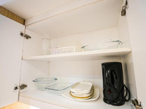 a small kitchen with white walls and white shelves at Casa Arabella - Wind Residences Tower 5 2018 in Tagaytay