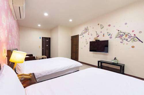 a bedroom with two beds and a flat screen tv at 甯好甯居NinGs HouSe in Yilan City